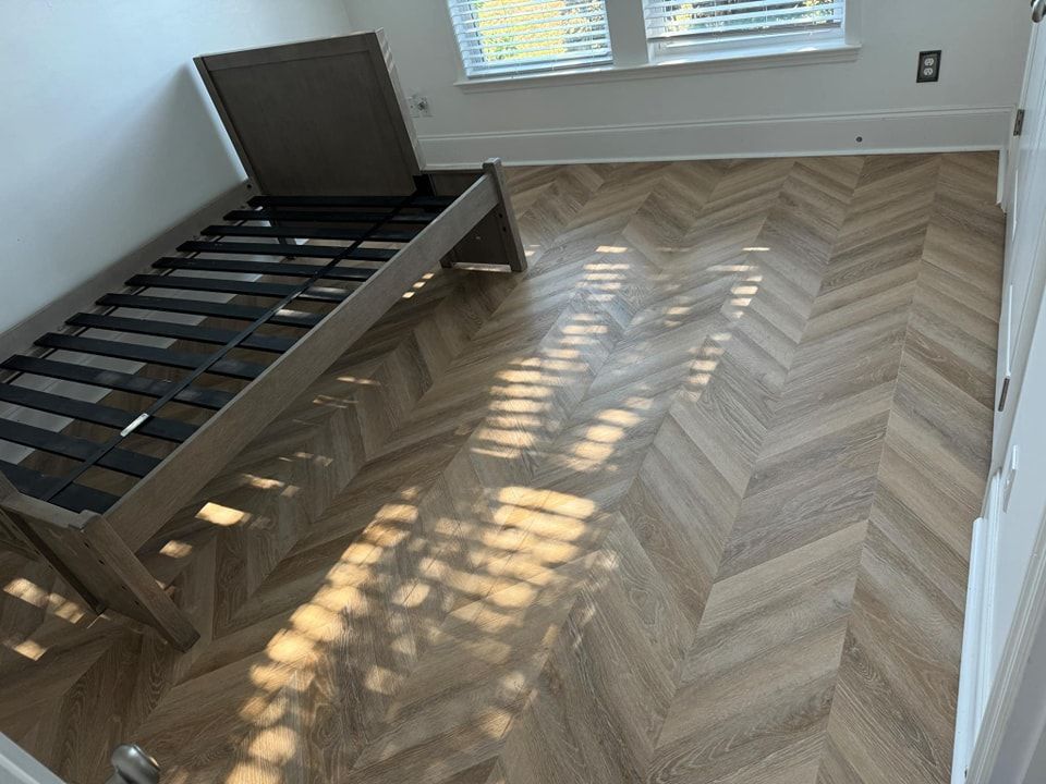 A bedroom with a bed and a herringbone floor