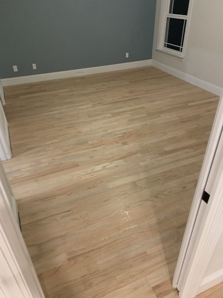 A bedroom with hardwood floors and a window.