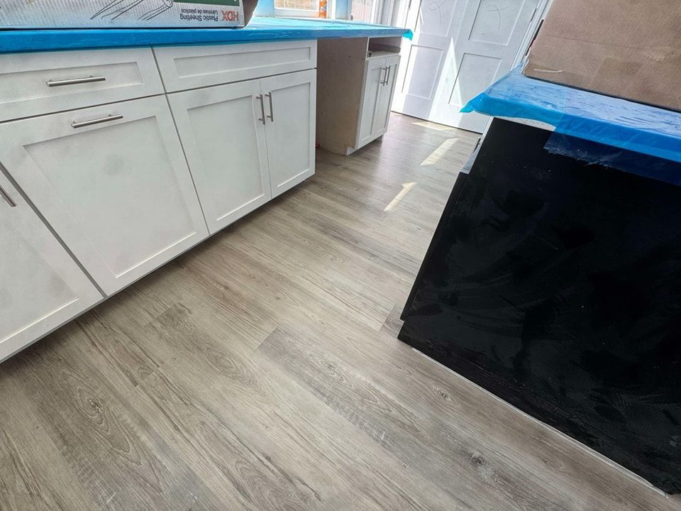 A kitchen with white cabinets and a wooden floor.