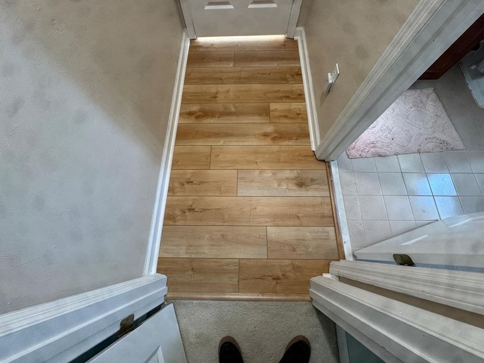 A person is standing on a wooden floor in a hallway.