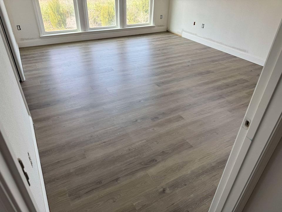 A large empty room with hardwood floors and windows.