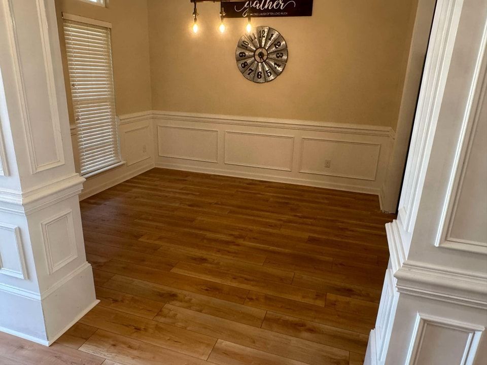 A dining room with hardwood floors and a clock on the wall.