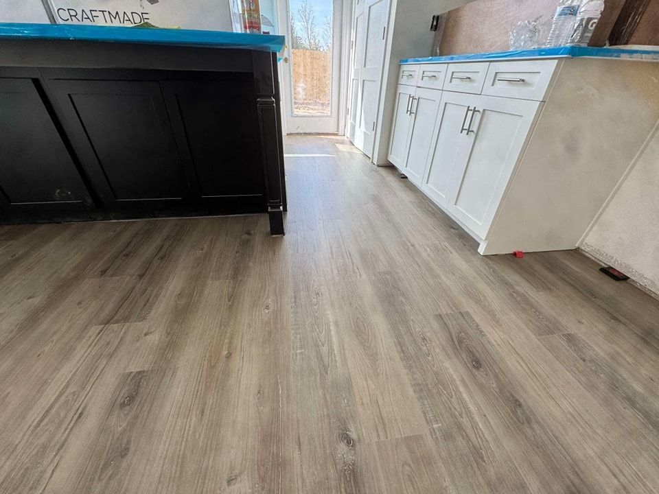 A kitchen with hardwood floors and black cabinets.