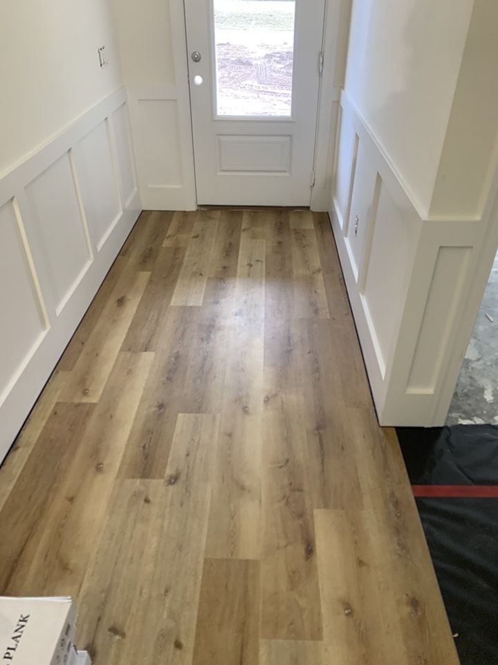 A hallway with a wooden floor and white walls.