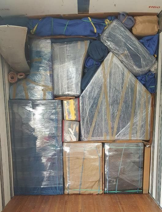 Packed shipping container with furniture and wrapped items, secured for transport.
