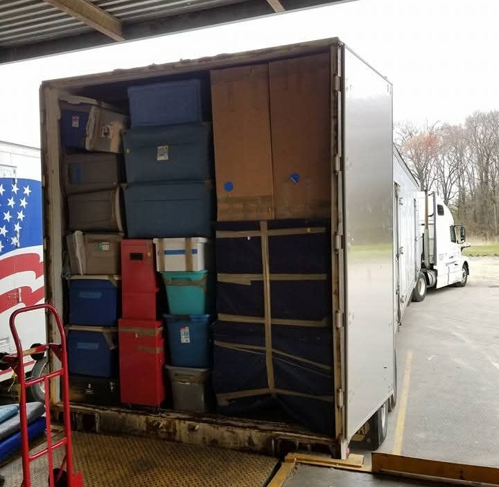 Boxes and containers carefully loaded into a truck trailer at a loading dock.