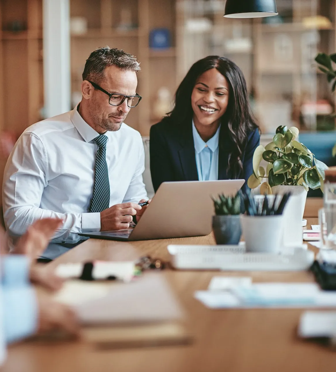 An effective HR strategy should be driving your growth. Two employees sitting at a conference room table engaged in a positive discussion in front of computer. Employee retention Houston HR consulting