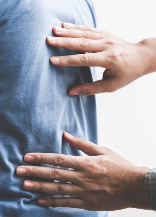 A chiropractor is holding another person 's back with their hands .