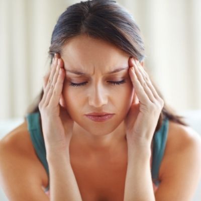 a woman is holding her head because she has a headache