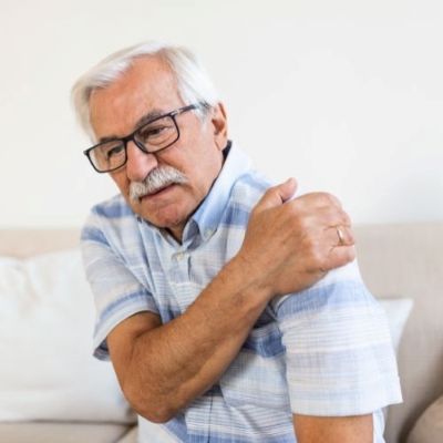 an older man  is holding his shoulder in pain
