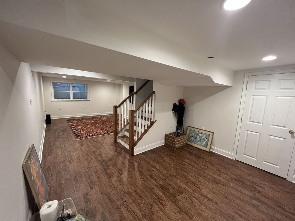 A basement with hardwood floors and stairs leading up to the second floor.
