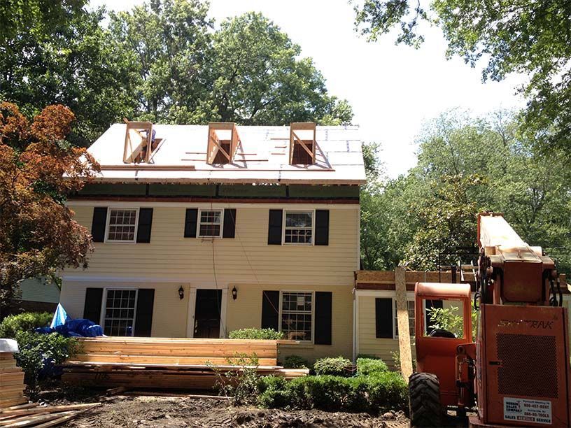A house that is being remodeled with a tractor in front of it