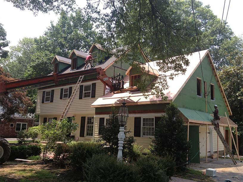 A house is being remodeled with a crane lifting the roof