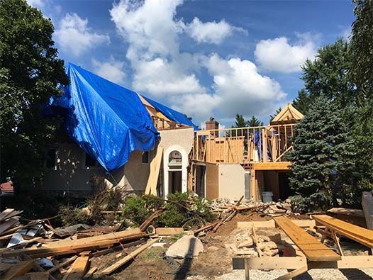 A house under construction with a blue tarp on the roof.