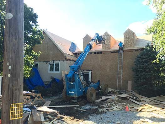 A house is being remodeled with a crane on the roof.