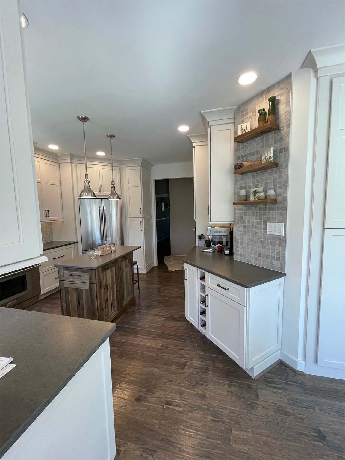 A kitchen with white cabinets and wooden floors and a large island.