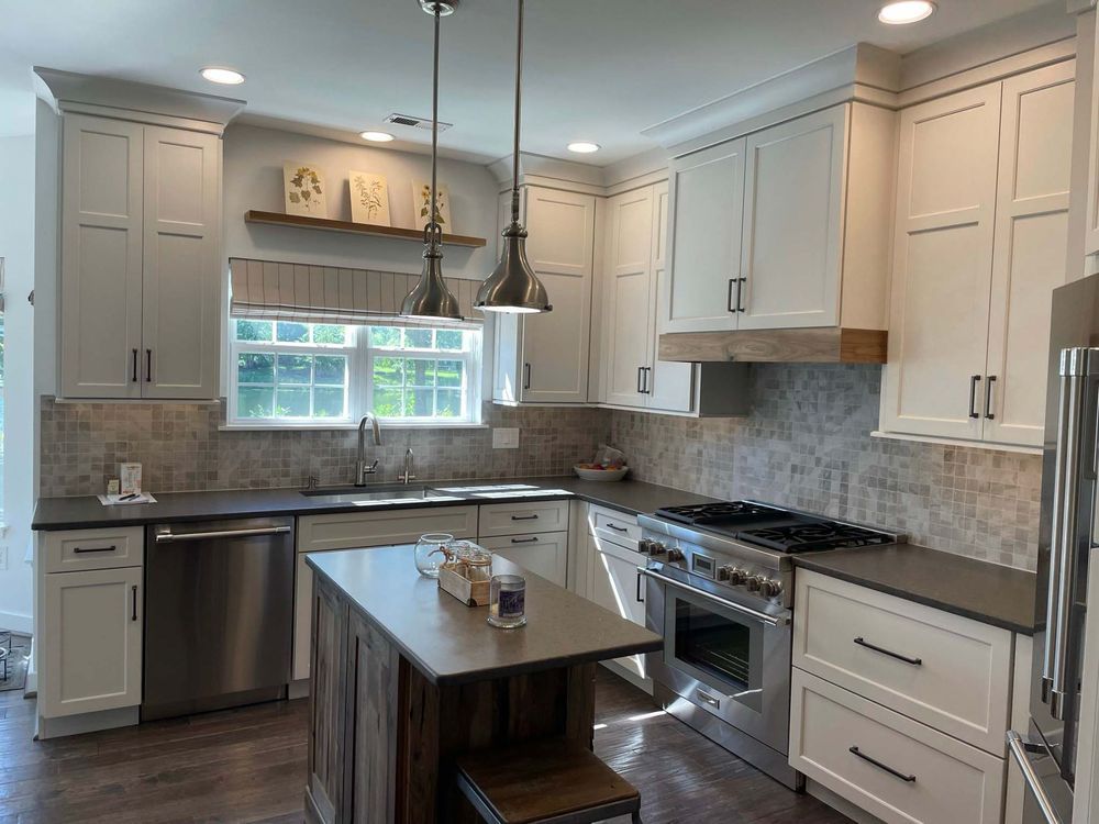 A kitchen with white cabinets , stainless steel appliances , and a large island.