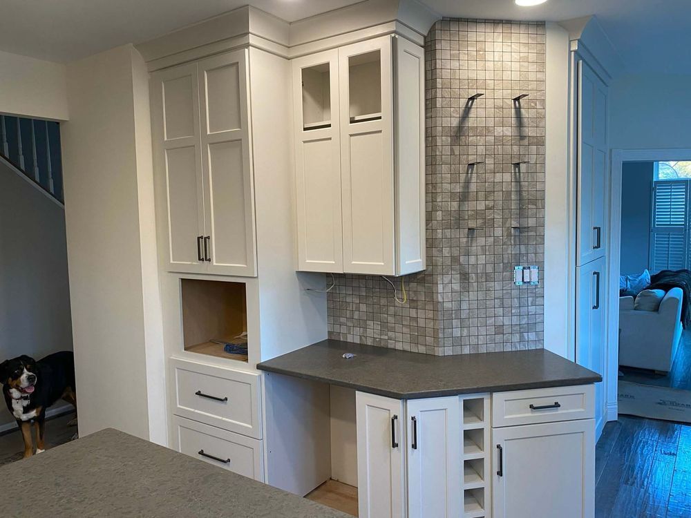 A kitchen with white cabinets and a dog in the background.