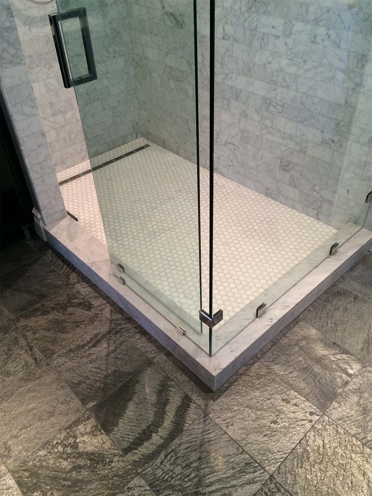 A walk in shower with a tiled floor and a glass door.