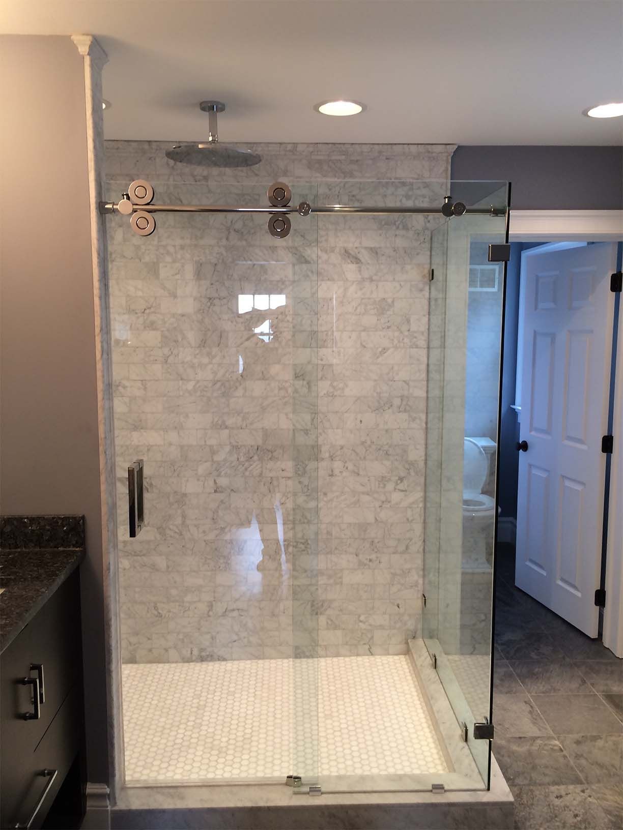A bathroom with a walk in shower with a sliding glass door.