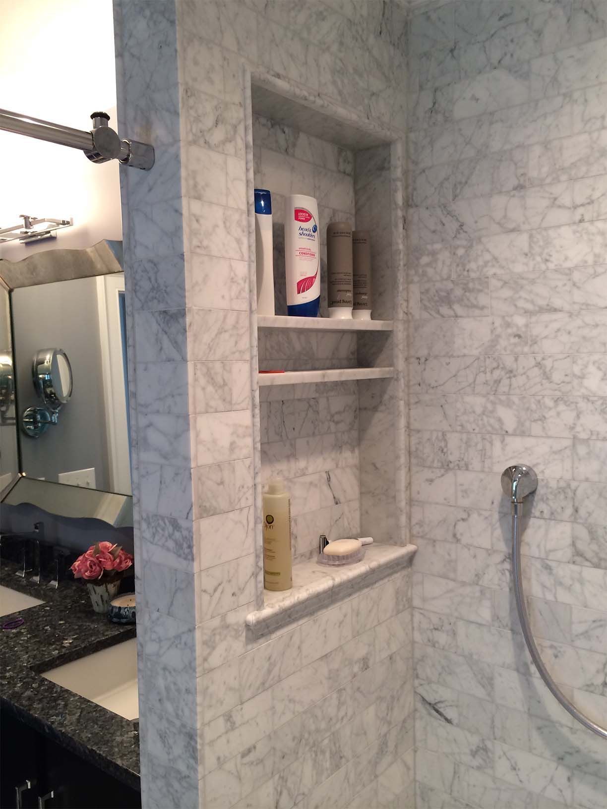 A bathroom with a shower and a shelf with shampoo on it