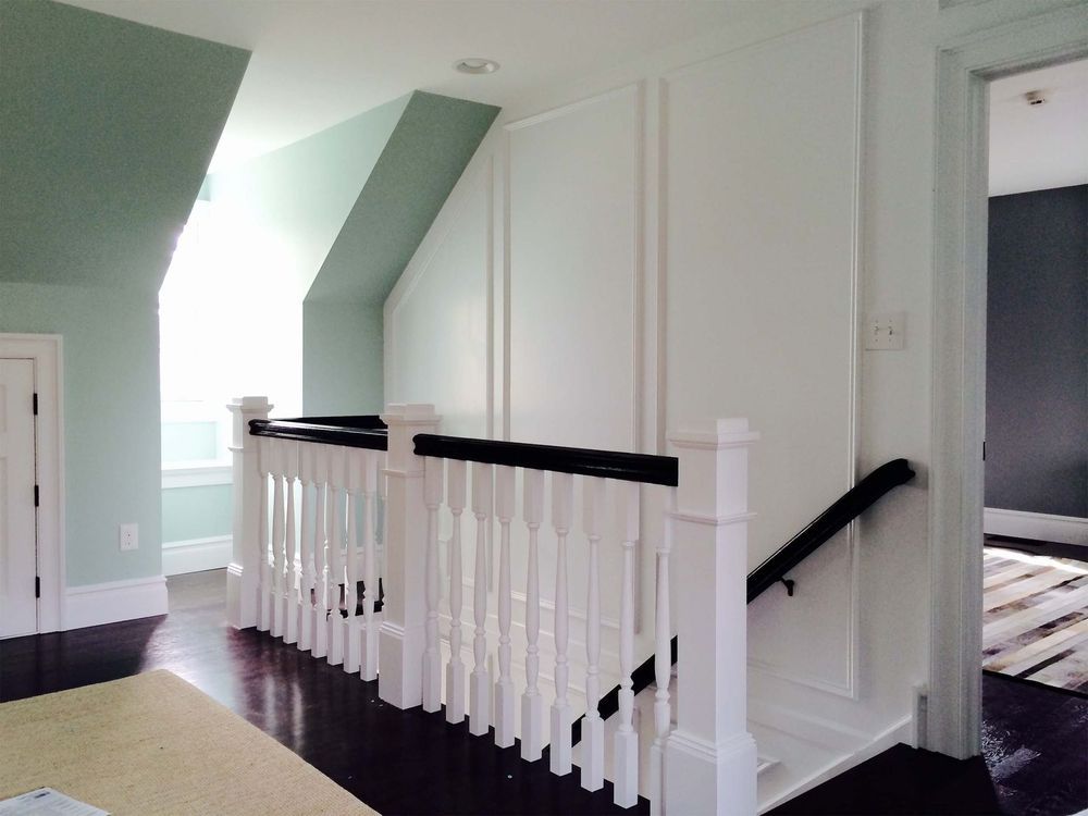 A staircase with a white railing and a black handrail