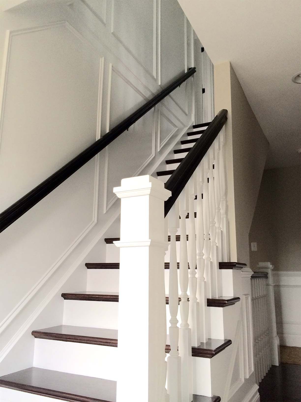 A white staircase with dark wooden steps and a black railing
