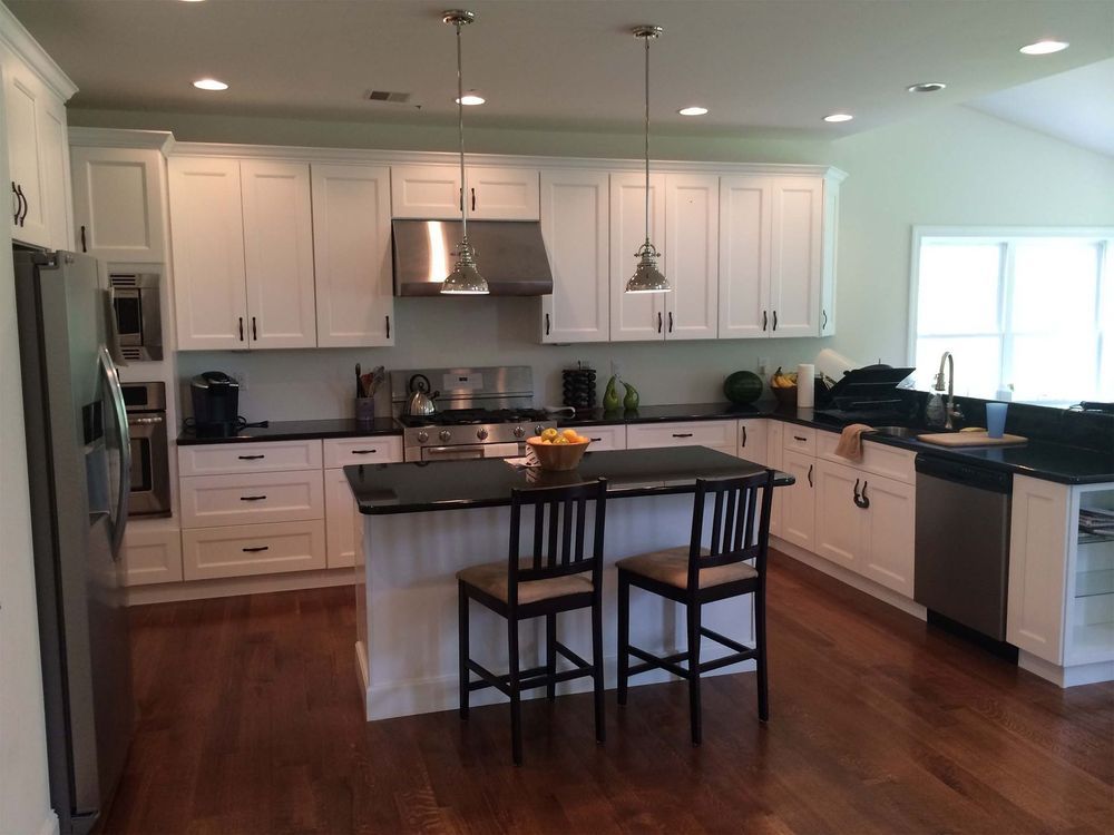 A kitchen with white cabinets and black counter tops