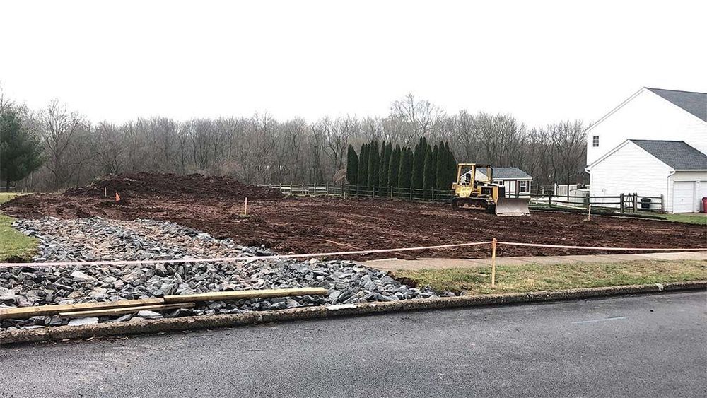 A large pile of dirt is sitting on the side of a road next to a house.