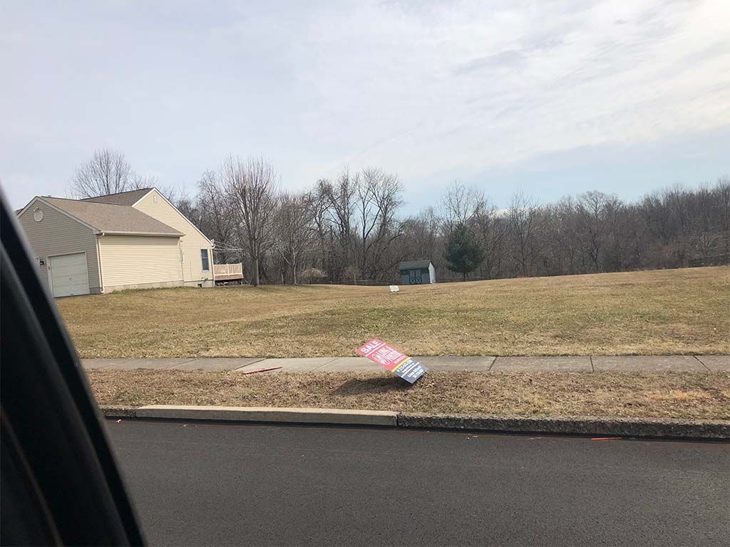 A flag is laying on the side of the road in front of a house.
