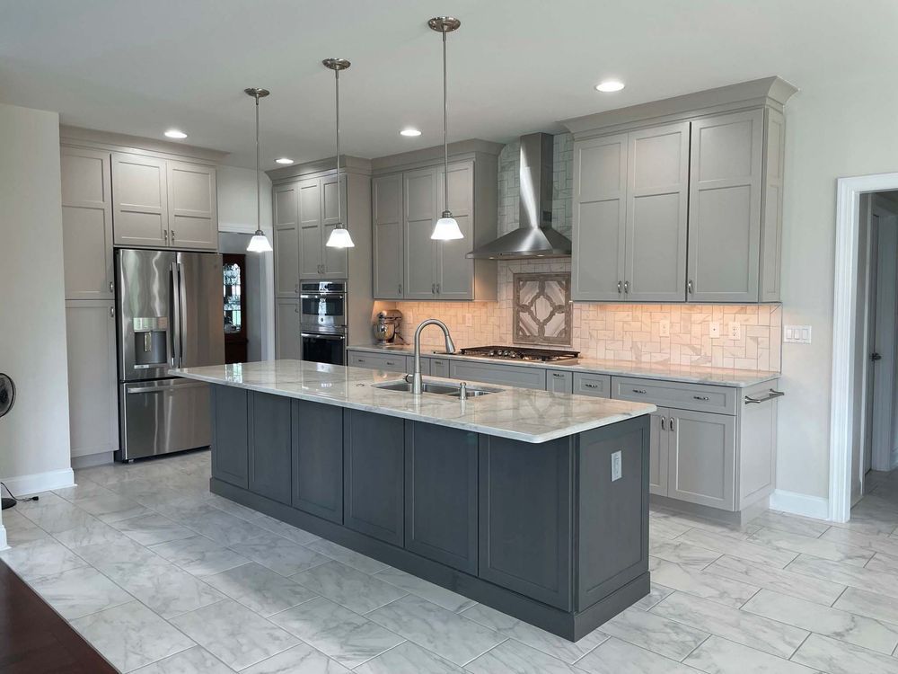 A kitchen with gray cabinets and a large island in the middle.