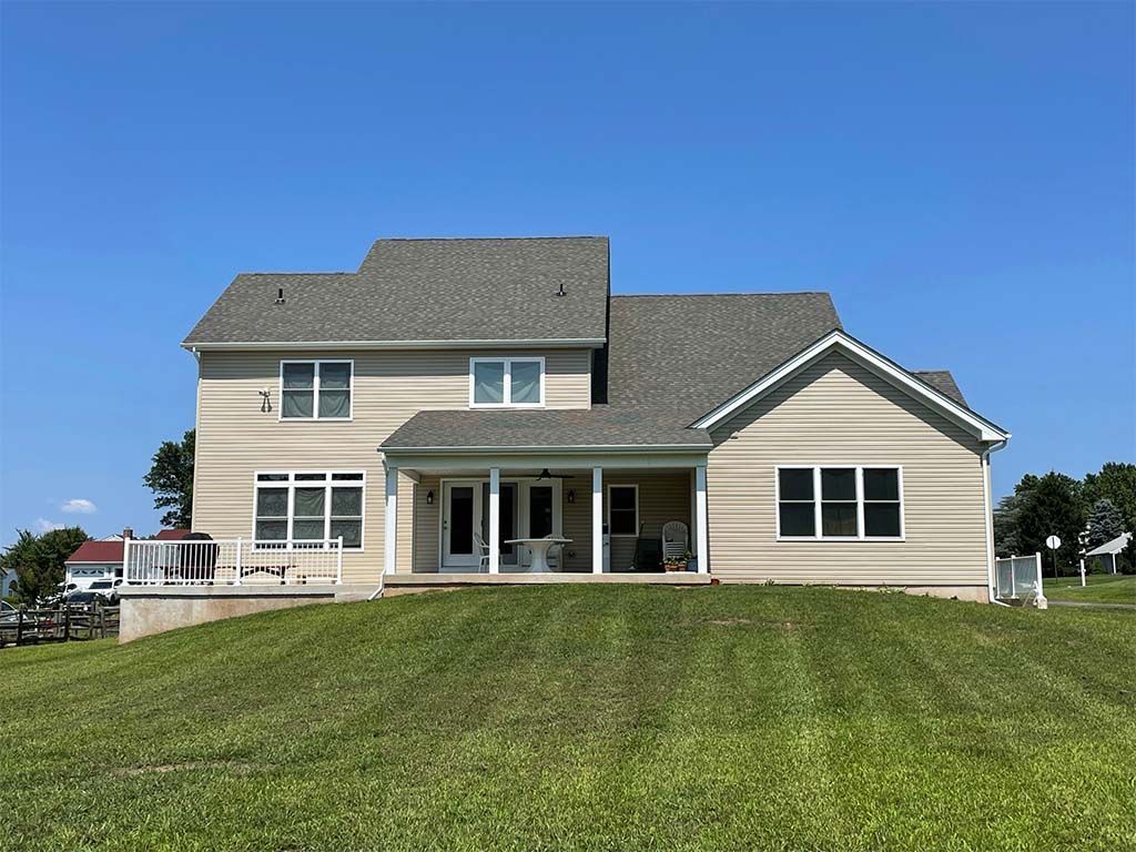A large house is sitting on top of a lush green hill.