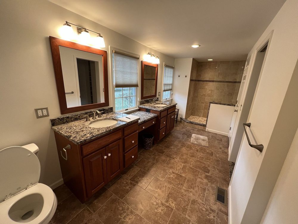 A bathroom with two sinks , a toilet and a shower.