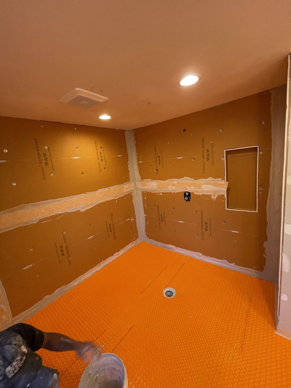 A man is painting a bathroom floor with a bucket.