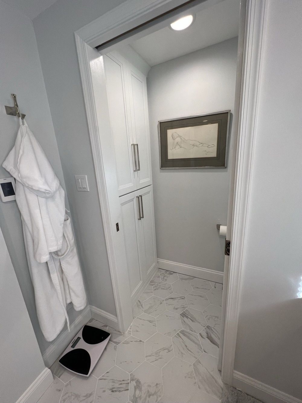 A bathroom with a bathrobe and a scale on the floor.