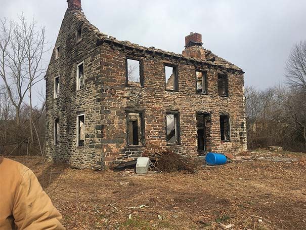 A man is standing in front of an old stone building
