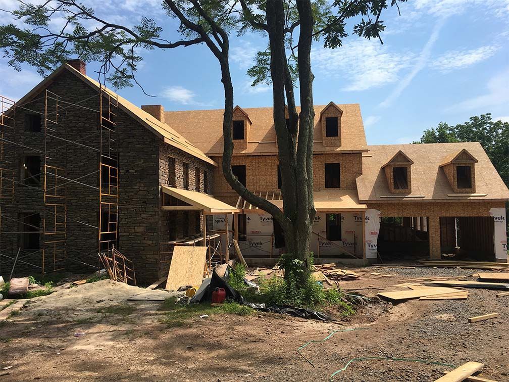 A large house is being built in the middle of a dirt field.