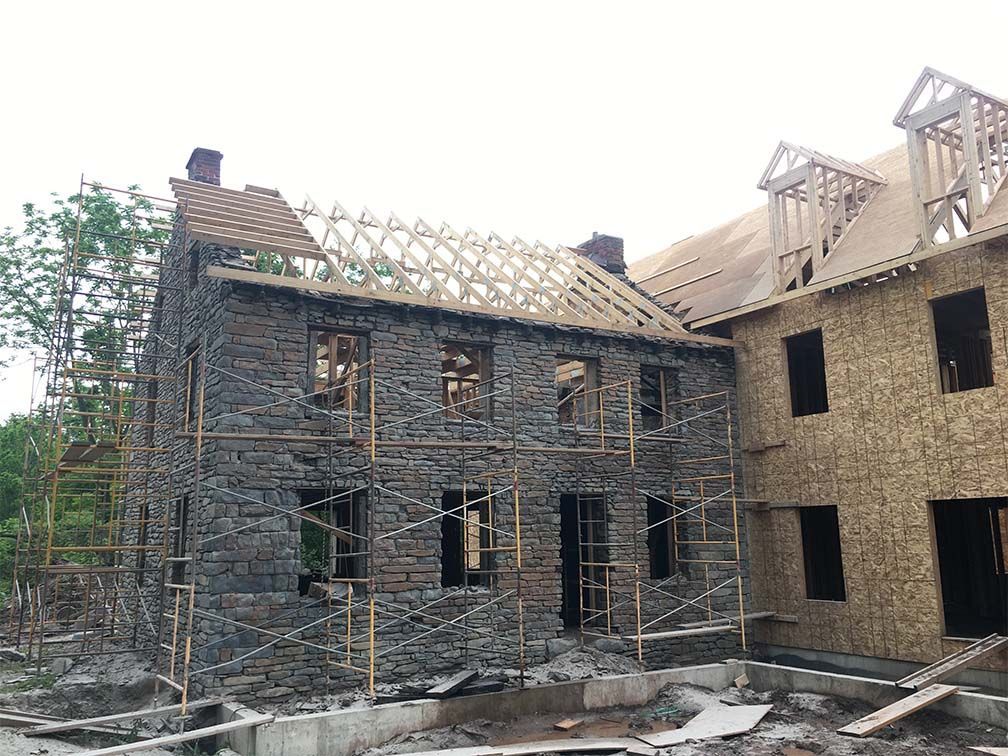 A large stone building under construction with a wooden roof.