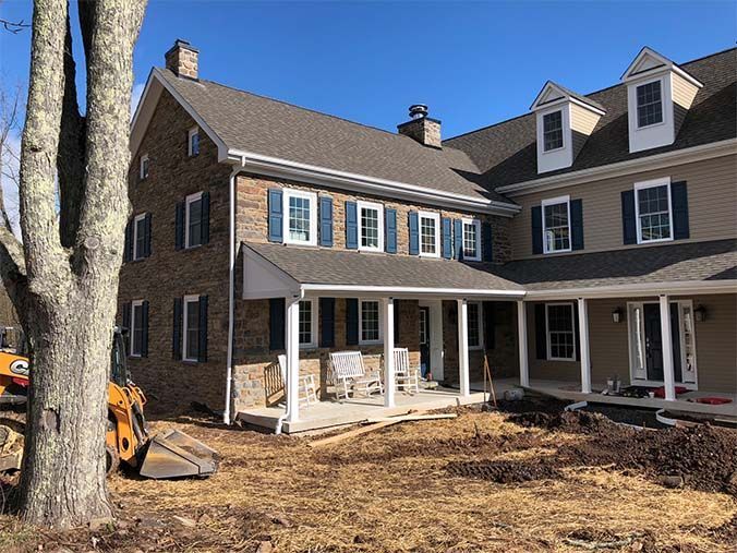 A large house with a porch and a tree in front of it.