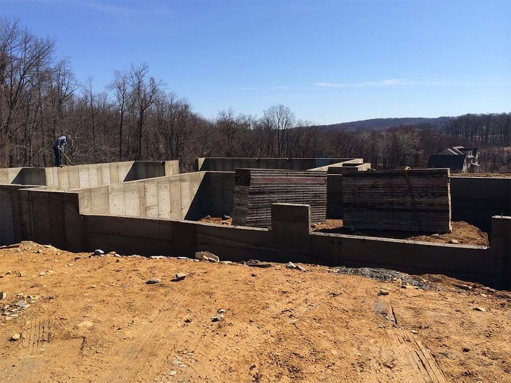 A concrete wall is being built in the middle of a dirt field.