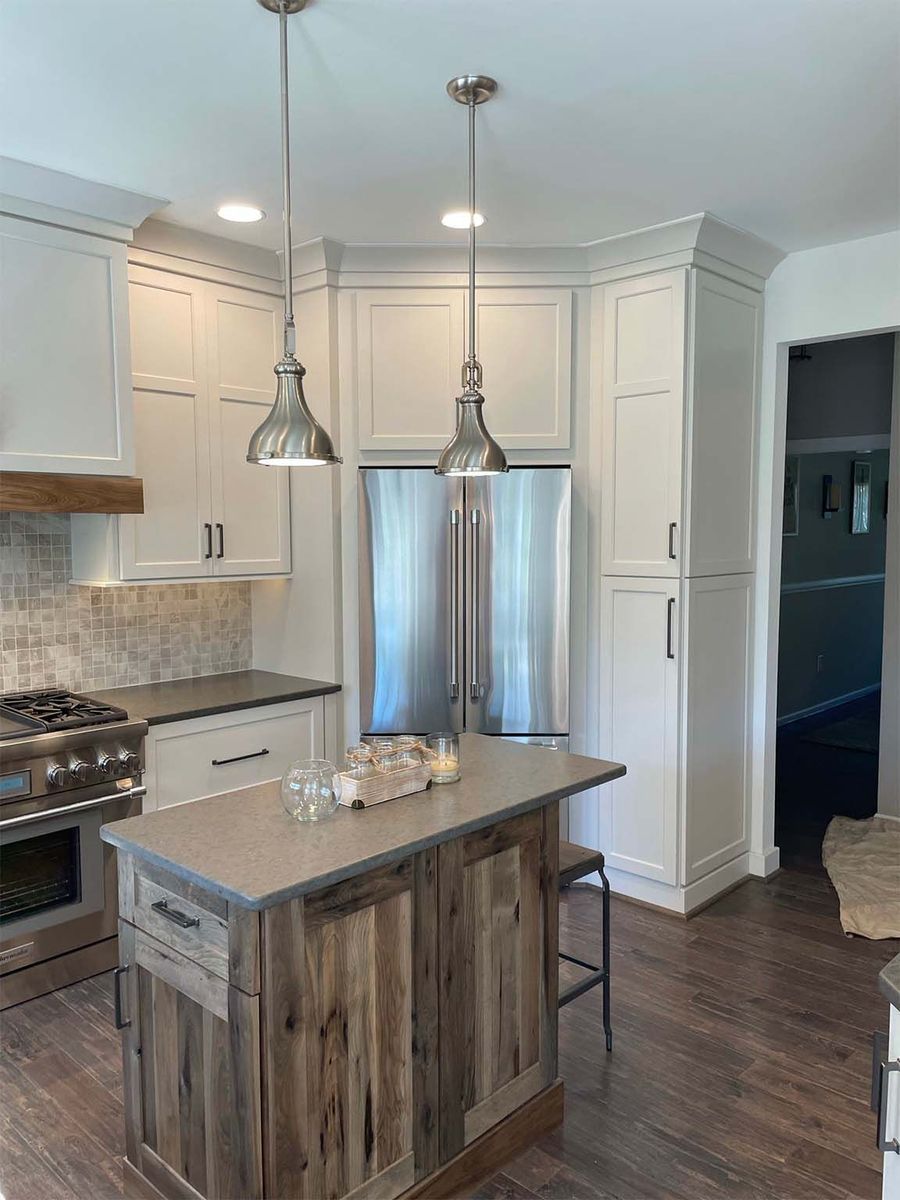 A kitchen with white cabinets , stainless steel appliances , and a wooden island.