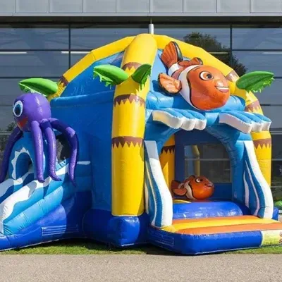 Kleurrijk opblaasbaar springkussen met octopusglijbaan, Nemo-figuren en palmboomaccenten.
