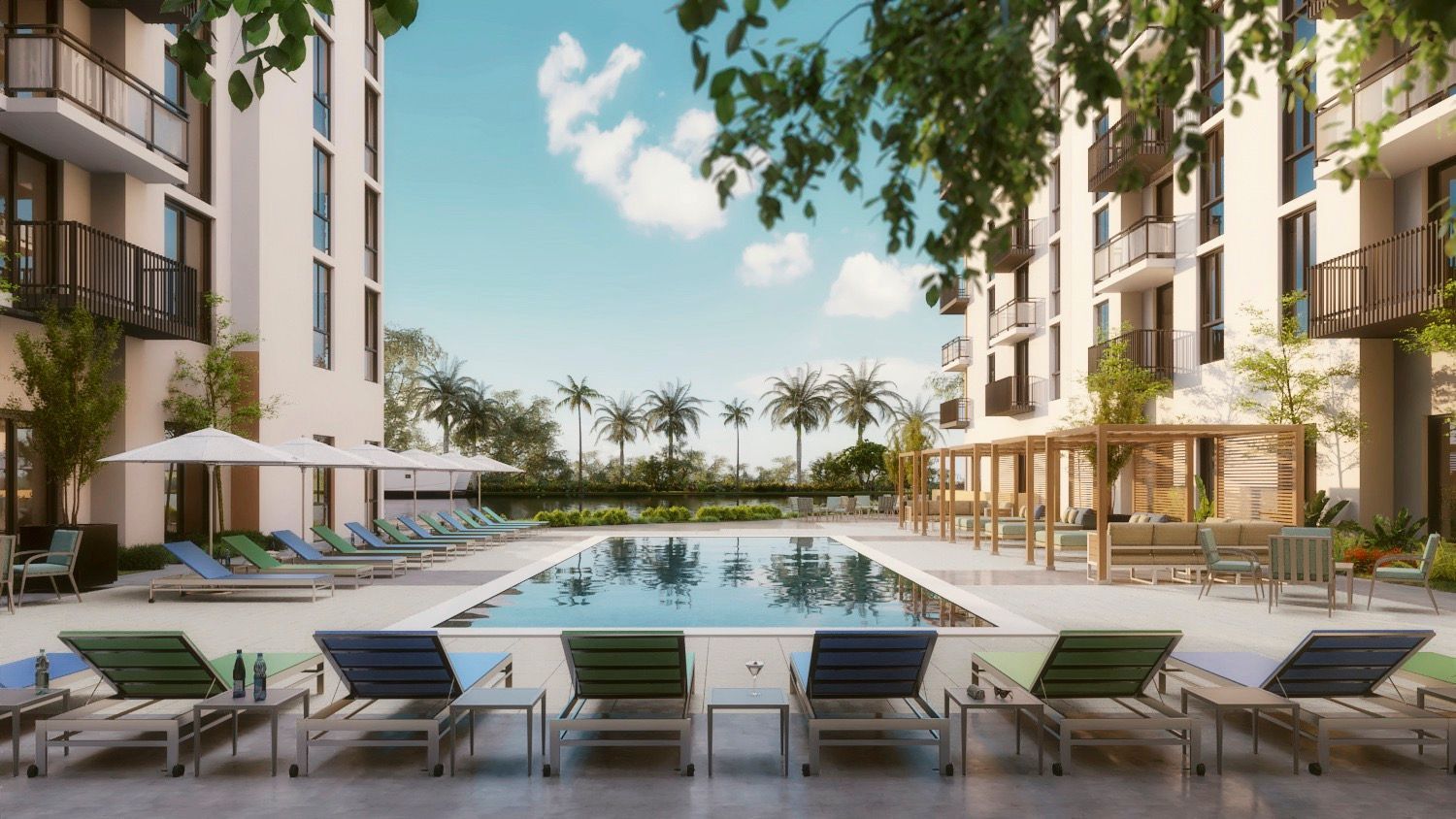 Swimming pool and lounge chairs between two apartment buildings under blue sky.
