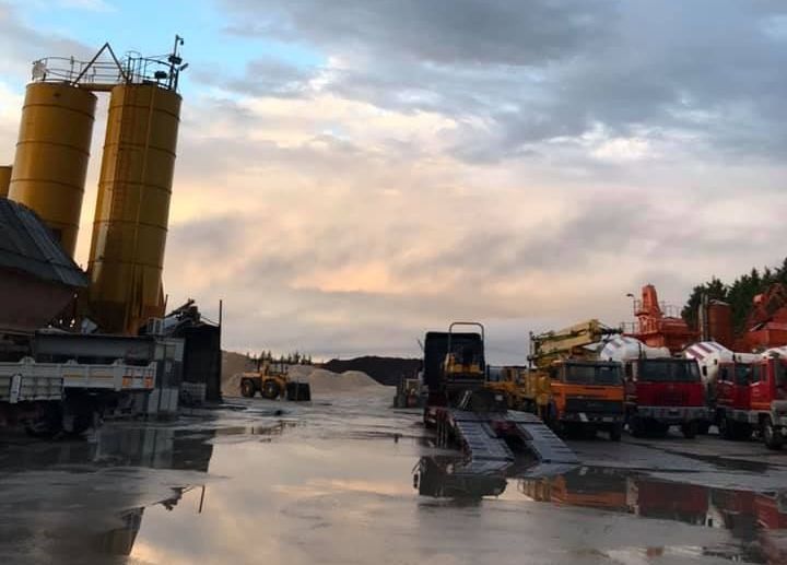 Molti camion sono parcheggiati in un parcheggio con un cielo nuvoloso sullo sfondo.