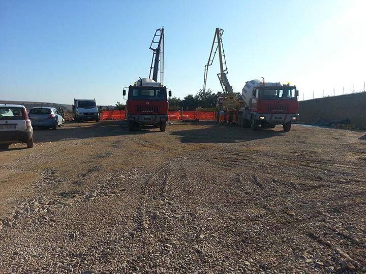 Due camion rossi sono parcheggiati in un piazzale ghiaioso