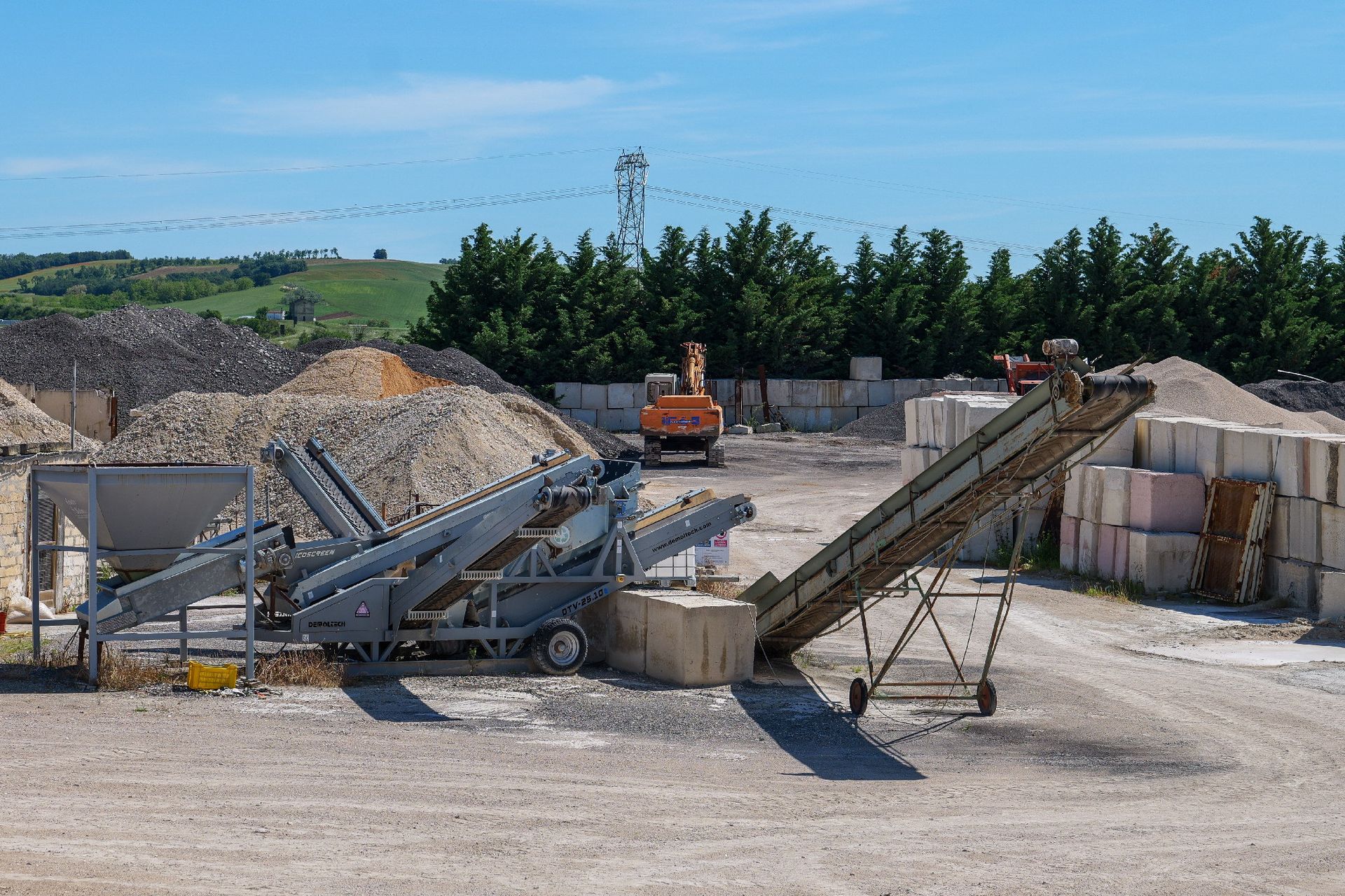 Impianto industriale di lavorazione della ghiaia con nastri trasportatori, cumuli di pietre ed un escavatore preventivo asfalti Centro Beton Potenza