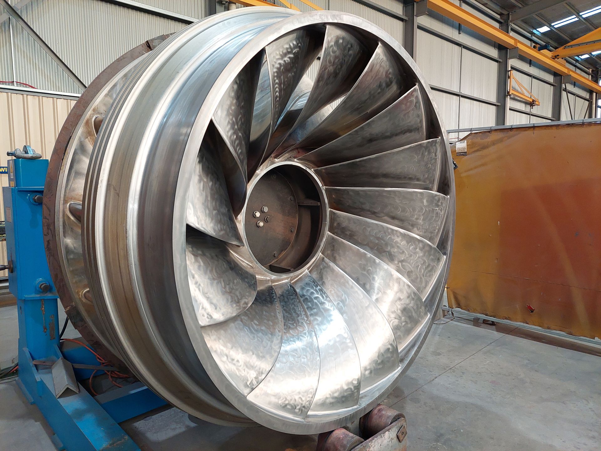 Large metal impeller with curved blades, in a workshop.