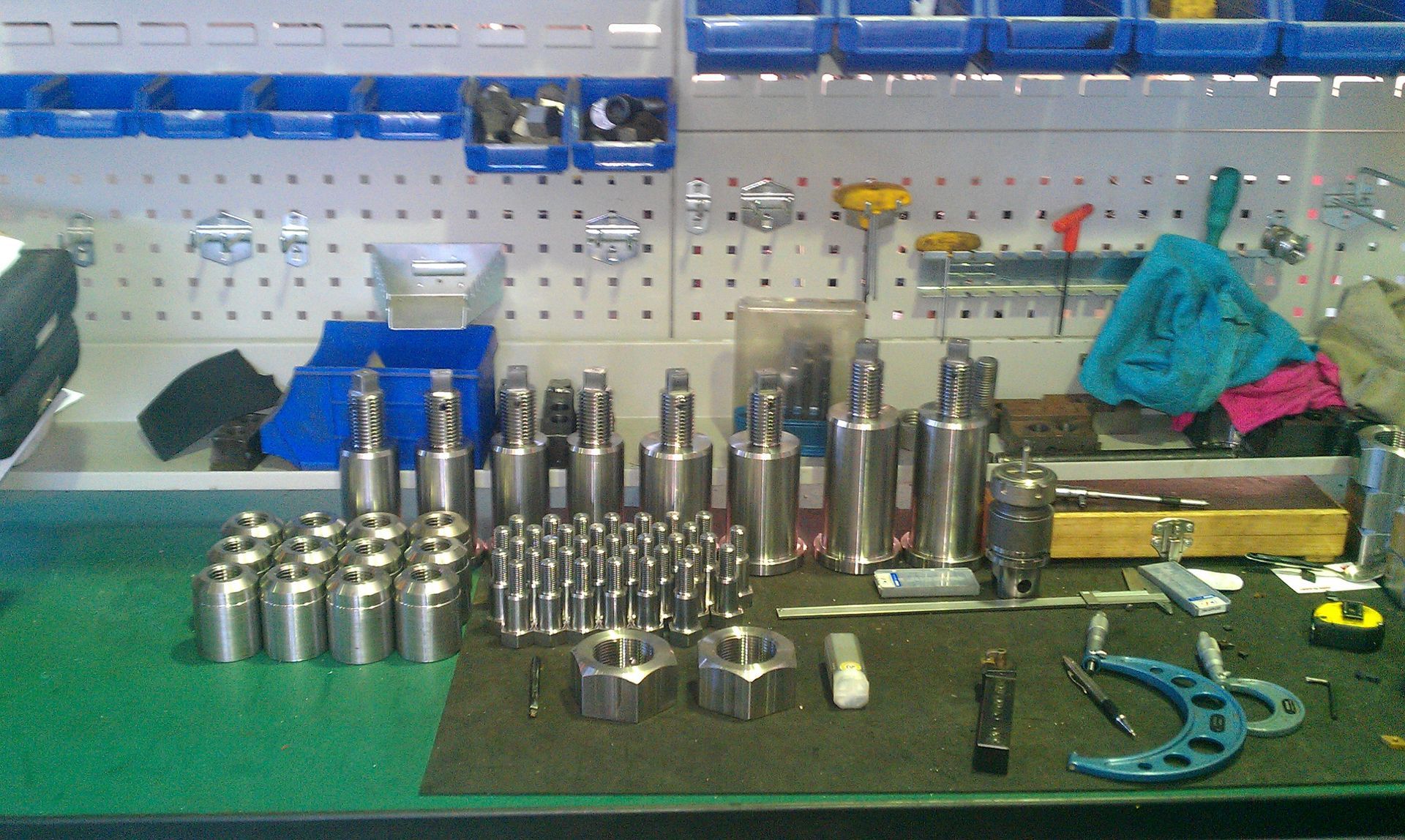 Workbench with machined metal parts and tools. Blue, silver, and green colors dominate the scene.