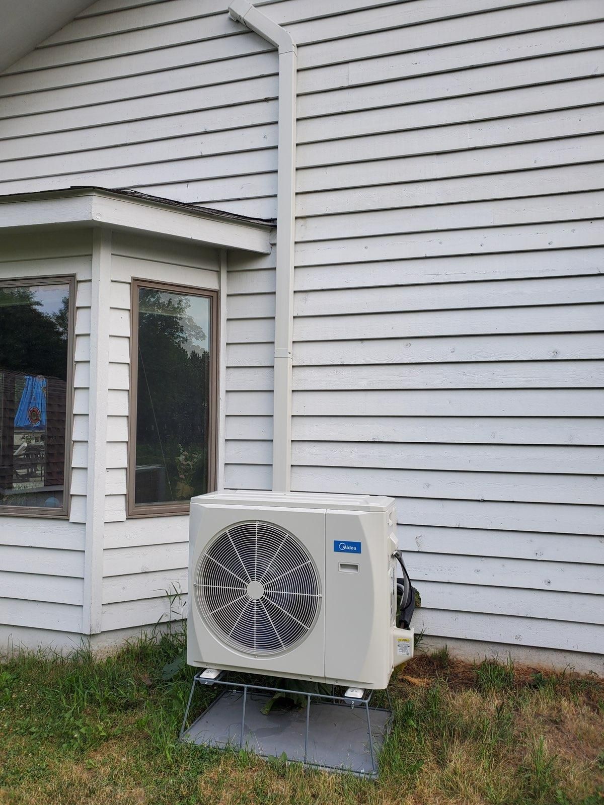 A white house with a large air conditioner on the side of it.