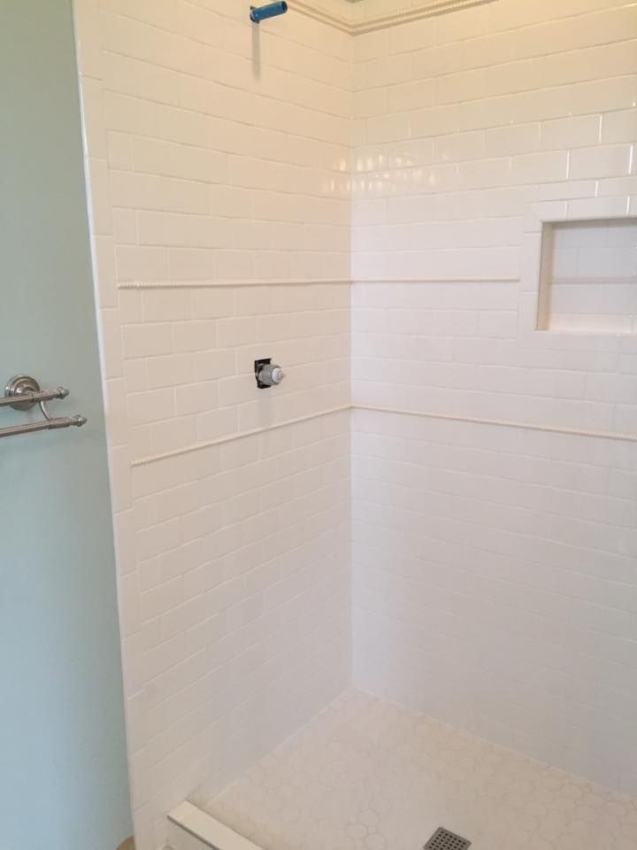 A bathroom with white tiles and a walk in shower.